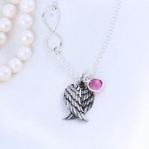 May include: A silver necklace with an infinity symbol charm, a heart-shaped angel wing charm, and a pink crystal charm.
