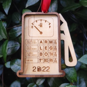 May include: A wooden gas pump ornament with a fuel gauge and a list of fuel types. The ornament is engraved with the text "ARM 9 10", "LEG 9 10", "BOTH 9 10", "1ST BORN 9 10", and "2022".