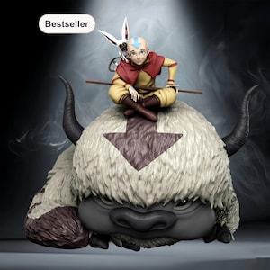 Op de afbeelding: Een beeldje van een personage uit Avatar: The Last Airbender. Het personage zit op een groot, harig wezen met hoorns. Het personage draagt gele en rode kleding en heeft een blauwe pijl op zijn hoofd. Het wezen heeft een grote pijl op zijn hoofd. Het woord "Bestseller" staat linksboven.