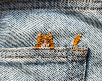 Schema PDF per ricamo a mano di un gatto rosso sulla tasca dei jeans, con video tutorial.