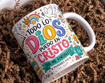 May include: A white ceramic mug featuring colorful hand-drawn illustrations including a rainbow, a dove, a crown, and a lightbulb. The text reads: Todo lo que puedo en Cristo que me fortalece, Filipenses 4:13, and other religious phrases.