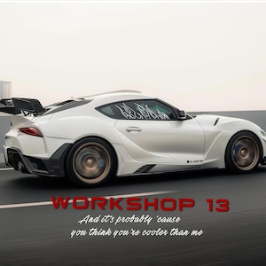 Puede incluir: Un coche deportivo blanco con modificaciones personalizadas, que incluyen un alerón trasero y calcomanías de llamas en la ventanilla lateral. El coche tiene llantas de color bronce y detalles en negro. El texto de la imagen dice "WORKSHOP 13" y una cita.