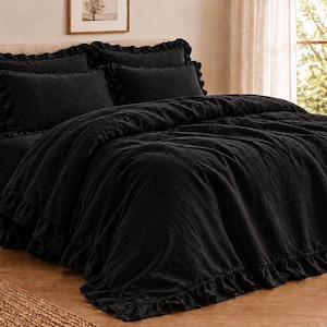 May include: A solid black bedding set featuring a duvet cover and matching pillow shams, all detailed with ruffled edges. The fabric has a textured, crinkled appearance, and the set is arranged neatly on a bed frame with a headboard.