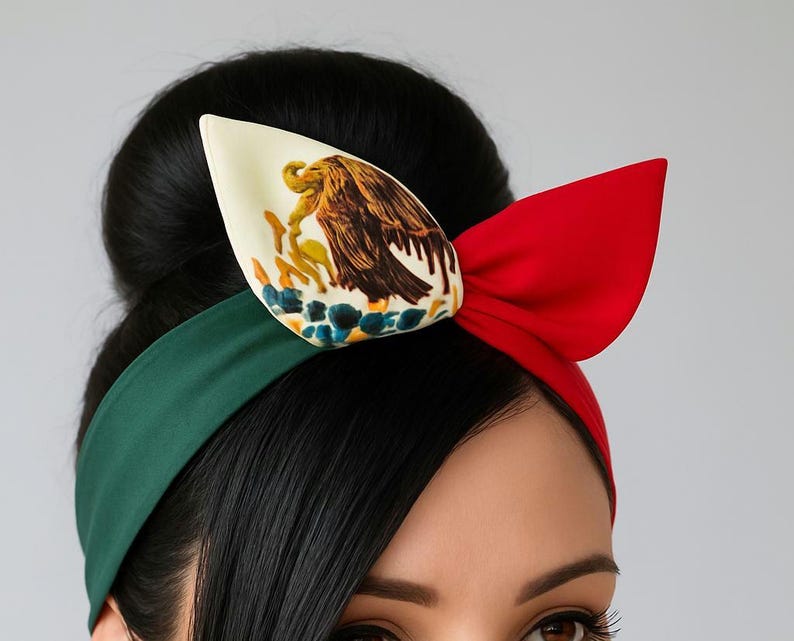 Puede incluir: Una diadema con una banda verde en el lado izquierdo y una banda roja en el derecho. En el centro, un lazo grande muestra una secci&oacute;n color crema con una ilustraci&oacute;n detallada de un &aacute;guila sobre un cactus, junto a una secci&oacute;n roja s&oacute;lida.