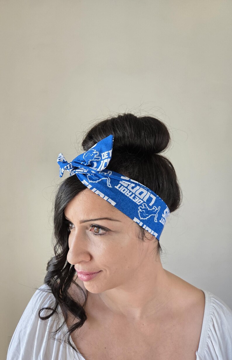 May include: A blue and white bandana headband with the text "DETROIT LIONS" and a lion graphic. The headband is tied around a woman's head.