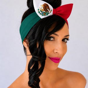Puede incluir: Una diadema con los colores de la bandera de M&eacute;xico, que presenta una banda verde y un lazo en la parte superior. El lazo est&aacute; dividido en tres secciones: blanca con el escudo nacional mexicano de un &aacute;guila sobre un nopal, y una roja.