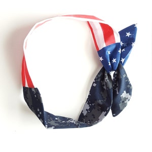 May include: A blue and white headband with a red, white and blue American flag design. The headband is tied in a knot at the top.