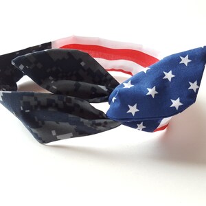 May include: A blue and white headband with a camouflage pattern on one side and a US flag pattern on the other side.