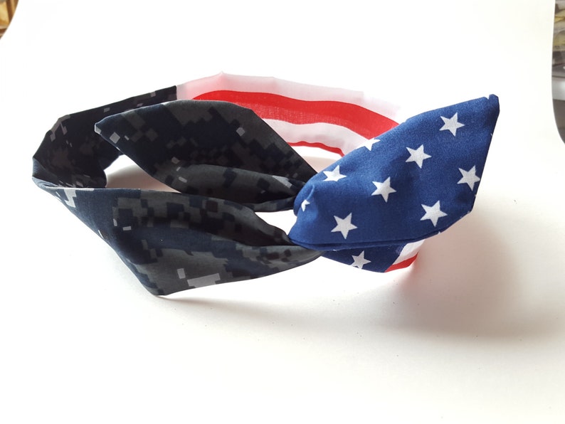 May include: A blue and white headband with a camouflage pattern on one side and a US flag pattern on the other side.
