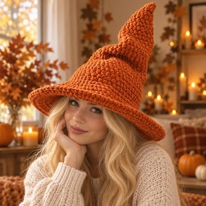 May include: A vibrant orange crocheted witch hat featuring a wide, slightly curved brim and a tall, pointed crown with a textured, chunky yarn stitch pattern. The hat is constructed from thick, soft-looking yarn in a solid, warm autumn color.