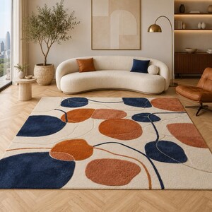 Könnte beinhalten: Ein rechteckiger Teppich mit einem abstrakten Muster aus großen, abgerundeten Formen in Marineblau und gebranntem Orange auf cremefarbenem Grund. Das Design enthält feine, fließende Linien, die die organischen Formen verbinden.