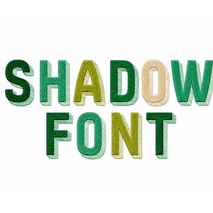 Op de afbeelding: De tekst SHADOW FONT wordt weergegeven in een blokkerig lettertype in borduurstijl. De letters hebben een gelaagd ontwerp met verschillende tinten groen, olijf en lichtbeige, wat een driedimensionaal effect creëert met een duidelijke slagschaduw.