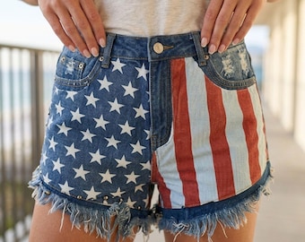 Pantaloncini in denim con stelle e strisce patriottiche: vita alta, orlo sfrangiato, perfetti per l'estate e i festival.
