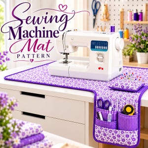 Op de afbeelding: Een witte naaimachine staat op een rechthoekige stoffen mat met een paars-wit bloemenpatroon. De mat heeft een zijverlenging met drie zakken voor naaigerei, een bijpassend speldenkussen met spelden en een paarse rand. Tekst Sewing Machine Mat PATTERN.