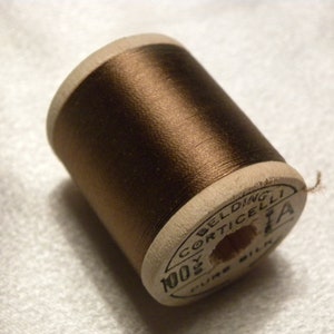 May include: A spool of brown thread with a white label that reads "Belding Corticelli 100% Pure Silk".