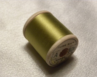 May include: A spool of olive green thread labeled "Pure Silk" with a price tag of 50 cents.