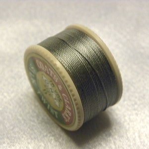 May include: A spool of Coats & Clark embroidery thread in a dark gray color. The spool is labeled "Coats & Clark Embroidery Floss".