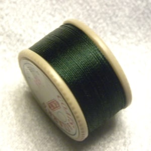 May include: A spool of dark green thread wound around a white plastic bobbin.