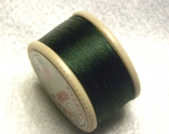 May include: A spool of dark green thread wound around a white plastic bobbin.