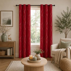 May include: A pair of floor-length red curtains featuring a vertical silver wavy line pattern, hung on a black rod with metal grommets. The curtains are opaque and drape in soft folds, framing a window that allows natural light into the room.