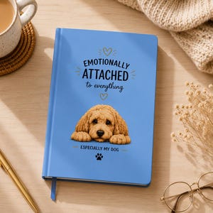 Può includere: Un diario blu chiaro con il testo "Emotionally Attached to Everything" e un'illustrazione di golden doodle. Il diario ha anche il testo "Especially My Dog" e un'impronta di zampa. Una penna d'oro, una tazza di caffè e occhiali sono anche nell'immagine.