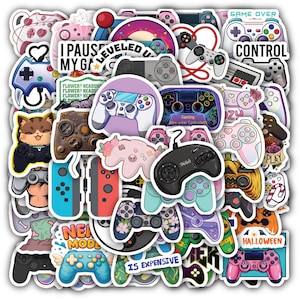 May include: A collection of colorful video game controller stickers. The stickers feature various designs, including controllers with floral accents, text like "GAME OVER" and "IS EXPENSIVE", and a cat holding a controller. The color palette includes pink, blue, and green.
