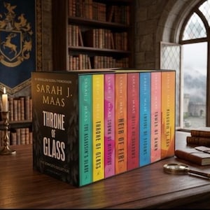 Può includere: Una collezione completa della serie di libri "Throne of Glass" di Sarah J. Maas. Il set include un cofanetto nero con il titolo della serie e il nome dell'autore, e i singoli libri hanno dorsi colorati. I libri sono esposti su un tavolo di legno.