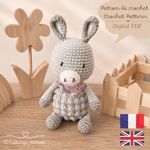 Peut inclure: Un âne en crochet gris avec un museau blanc, des yeux noirs et un bandana à motif floral rose autour du cou. Le texte indique : Patron de crochet, Crochet Pattern, Digital PDF et Couturage_crochete.