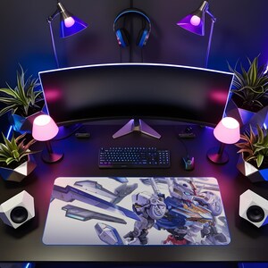 May include: A gaming desk setup featuring a curved monitor, black keyboard, and mouse. A large rectangular desk mat displays a detailed illustration of a white and blue robot with mechanical components. Two small lamps, two speakers, and four potted plants surround the equipment, with headphones hanging above the monitor.