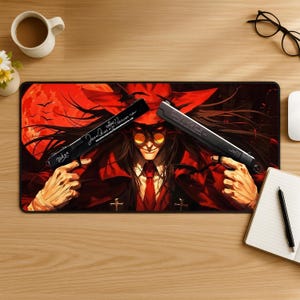 May include: A rectangular desk mat featuring a vibrant illustration of a character with long dark hair, wearing a red coat and round yellow glasses, holding two black handguns. The guns are inscribed with the text "Tsukon" and "Hellsing Arms".
