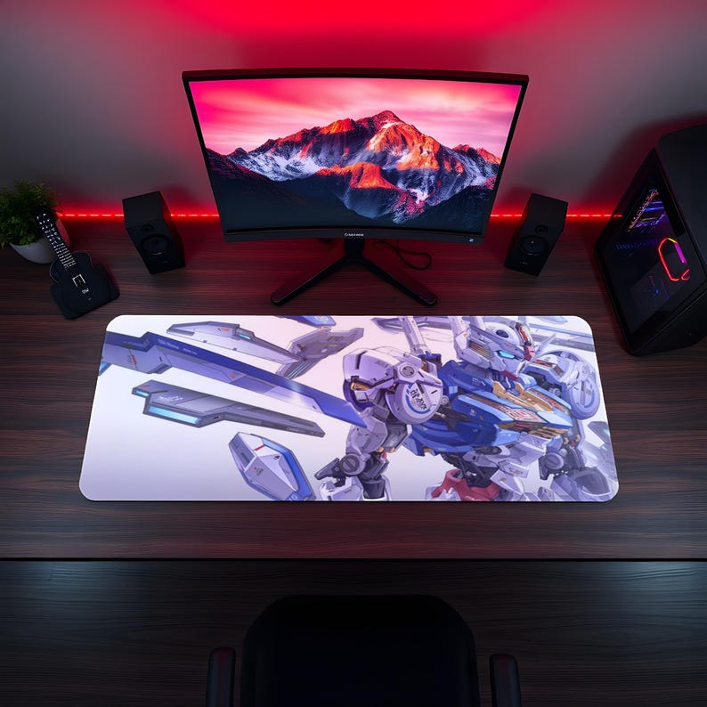 May include: A rectangular desk mat featuring a detailed illustration of a white, blue, and gold robotic figure with mechanical armor components floating around it, set against a light background on a dark wood surface.