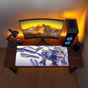 May include: A rectangular desk mat featuring a detailed illustration of a white, blue, and red robotic figure with mechanical components and sharp geometric shapes. The mat is positioned on a dark wood desk surface in front of a computer monitor.