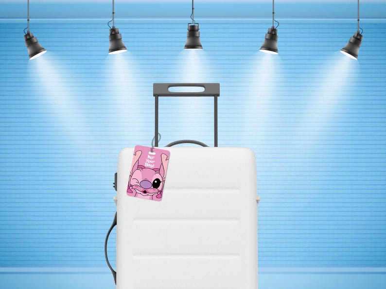 May include: A white hard-shell suitcase with a retractable handle and a pink luggage tag attached. The tag features a graphic of a pink cartoon character winking with the text "For Your Bag!" printed in white letters on the front surface.