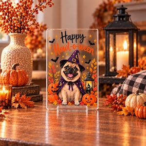 May include: A rectangular clear acrylic sign featuring a printed illustration of a pug wearing a purple witch hat and cape. The text "Happy Howl-o-ween" is printed in black and orange. The design includes orange pumpkins, autumn leaves, bats, and a lantern.