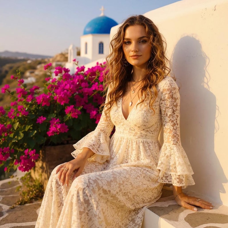 May include: A long-sleeved cream-colored lace dress featuring a deep V-neckline and tiered bell sleeves. The garment is crafted from intricate floral lace fabric, extending to a full-length skirt with a fitted bodice and a defined waistline.
