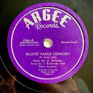 May include: A black vinyl record with a circular purple label featuring the text ARGEE Records, 1066-A, NON-BREAKABLE, Russian-Vocal, BELEYET PARUS ODINOKY (A Lonely Sail), Music by: A. Varlamov, Sung by: I. Kozlovsky with Piano Accomp., recorded in Europe, Made in USA.