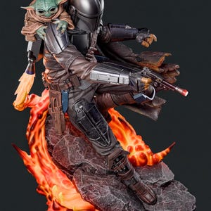 A detailed statue depicting a character in a futuristic, space-themed outfit, holding a weapon and accompanied by a small alien-like creature.