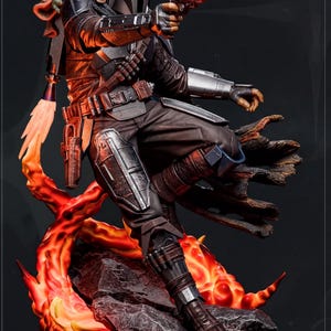 A detailed statue of a character from the Star Wars franchise, holding a gun and accompanied by a small alien-like creature.