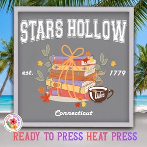 May include: A grey graphic print featuring the text Stars Hollow est. 1779 Connecticut. The design includes a stack of five colourful books tied with an orange ribbon, surrounded by autumn leaves and a brown coffee mug labelled Luke's.