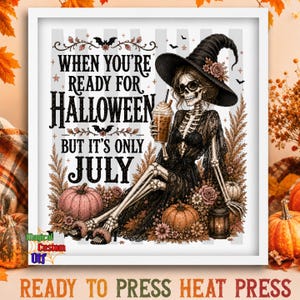 Peut inclure: Une impression encadrée montrant un squelette portant un chapeau de sorcière et une robe en dentelle noire, tenant un café glacé. Le texte indique : WHEN YOU'RE READY FOR HALLOWEEN BUT IT'S ONLY JULY. Décor de citrouilles, fleurs et lanterne.