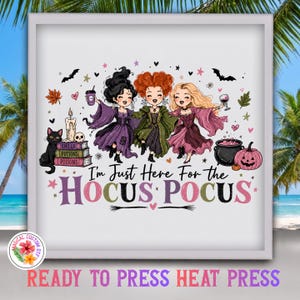 May include: A white framed print featuring three cartoon witches in purple, green, and pink dresses. The text reads I'm Just Here For The HOCUS POCUS. Includes a black cat, a stack of books, a candle, a skull, a cauldron, and a pink pumpkin.