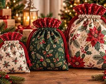 May include: Three fabric drawstring gift bags in varying sizes, featuring festive patterns of red poinsettias, green pine needles, and holly berries on cream and dark green backgrounds, finished with red velvet-textured drawstring tops.
