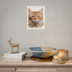 Puede incluir: Una impresión de pared rectangular que presenta una ilustración detallada de un gato atigrado naranja con ojos verdes. El gato tiene rayas distintivas y bigotes largos, representados en un estilo pictórico sobre un fondo claro y liso.