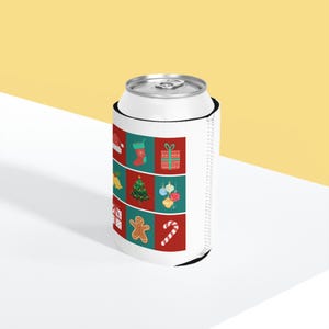Puede incluir: Un enfriador de latas de espuma blanca con una cuadrícula de nueve iconos navideños que incluyen un gorro de Papá Noel, un calcetín, una caja de regalo, campanas, un árbol de Navidad, adornos, otro regalo, un hombre de jengibre y un bastón de caramelo.