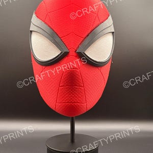 May include: A red textured mask with black eye frames and white mesh lenses, featuring a web pattern across the surface. The mask is displayed on a black stand and includes the repeated watermark text CRAFTYPRINTS across the image.