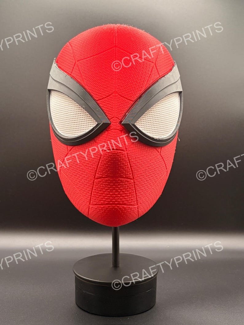May include: A red textured mask with black eye frames and white mesh lenses, featuring a web pattern across the surface. The mask is displayed on a black stand and includes the repeated watermark text CRAFTYPRINTS across the image.