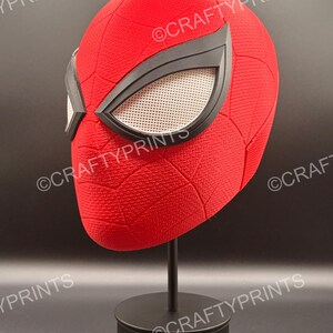 May include: A red textured full-head mask featuring a black web pattern and large, angular black-rimmed eye lenses with white mesh inserts. The mask is mounted on a black display stand. The text CRAFTYPRINTS is visible across the image.