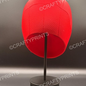 May include: A bright red, textured, rounded head covering with a web-like pattern, displayed on a black stand. The text CRAFTYPRINTS is visible multiple times across the image. The object has a smooth interior and a structured, dome-shaped exterior.