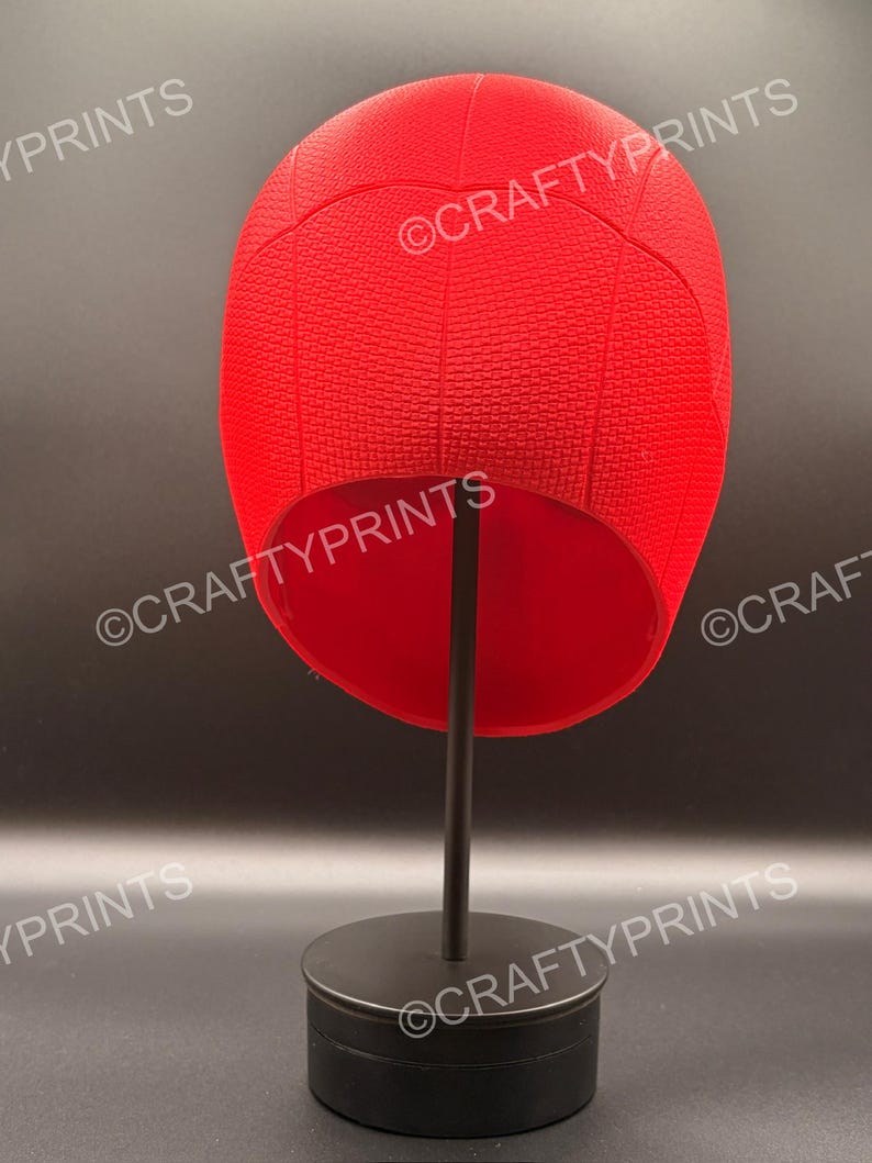 May include: A bright red, textured, rounded head covering with a web-like pattern, displayed on a black stand. The text CRAFTYPRINTS is visible multiple times across the image. The object has a smooth interior and a structured, dome-shaped exterior.