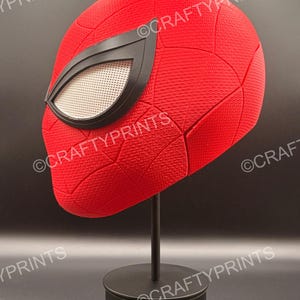 May include: A red textured full-head mask featuring a black web pattern and large white mesh eye lenses with black frames. The mask is displayed on a black stand. The text CRAFTYPRINTS is visible multiple times across the image surface.
